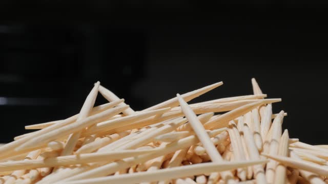 Bamboo toothpicks on a dark background. Wooden sticks for cleaning teeth