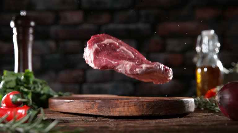 Flying piece of raw beef steak falling on cutting board.