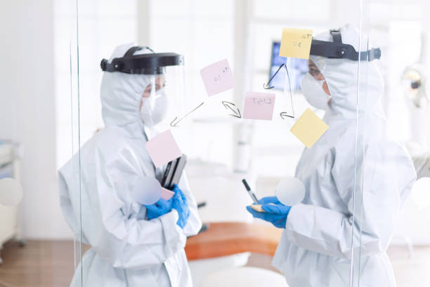 istock Tired dentist discussing about patient diagnosis wearing ppe suit 1867342503