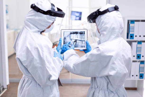 istock Dentistiry team in ppe suit holding tablet with teeth digital xray 1867343628