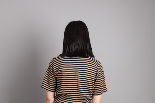 The young adult Asian woman standing on the grey background