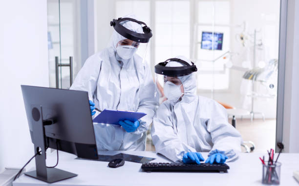 istock Dentist and nurse during global outbreak in protective suit 1867349066