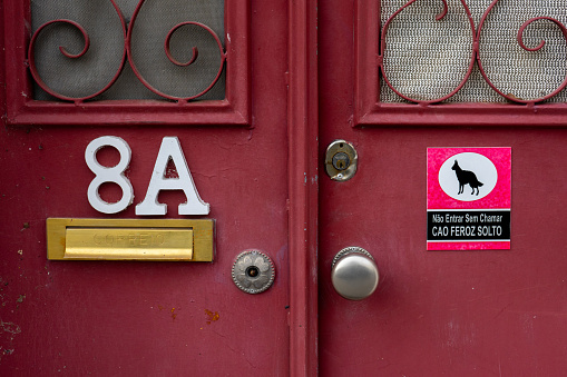 Door with sign 'Do not enter without knocking, fierce dog on the loose'.