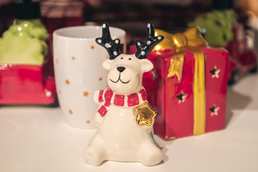 Funny Christmas ceramic reindeer on a souvenir shelf. Buying gifts and souvenirs for the holiday, Christmas shopping, toys in a decor store.