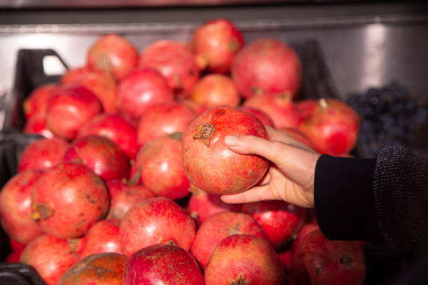 A woman chooses pomegranate fruit at a grocery store.