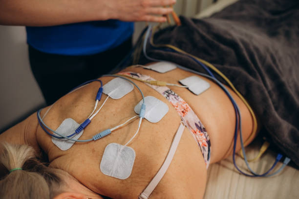 Lower Back Physical Therapy with TENS Electrode Pads, Transcutaneous Electrical Nerve Stimulation. Electrodes onto Patient's Lower Back