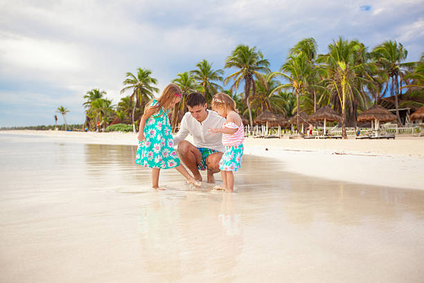 istock Father and his adorable little daughters playing on the beach 186739397