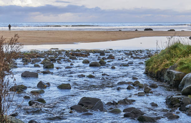 Water running over basalt rocks to the sea at Downhill Beach stock photo