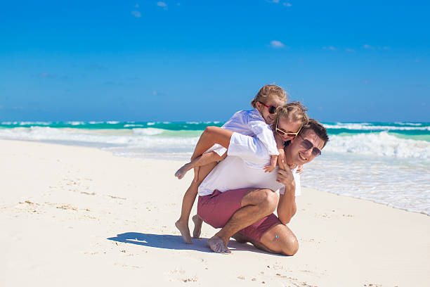 istock Father and daughters having fun on beach in sunny day 186741336
