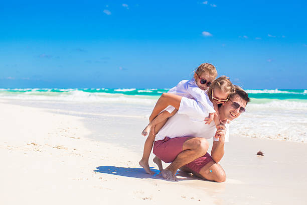 istock Happy father and little daughters having fun on beach 186741340