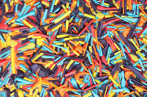 Stock photo showing close-up, elevated view of rainbow coloured sugar strand sprinkles used for the decoration of cakes.