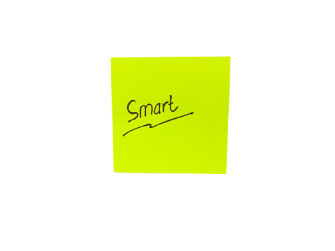 handwritten with the word smart written on a small yellow note useful for self-encouragement and self-development, in a photo in flatlay style on a white background