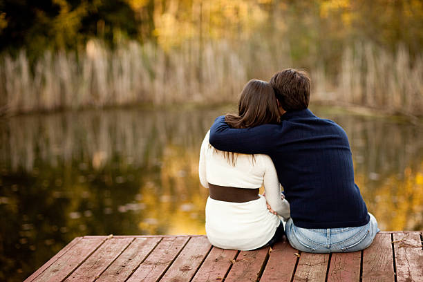 istock Couple Sitting Together on Deck Overlooking Pond, in Autumn 186743926