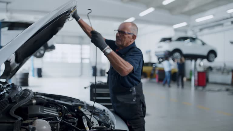 Male mechanic examining car engine in auto repair shop