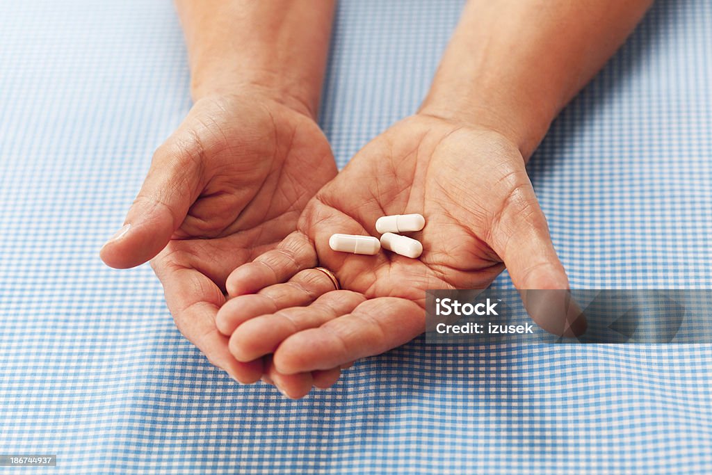 Medicines in hand Close up of elderly hand holding pills. 60-64 Years Stock Photo