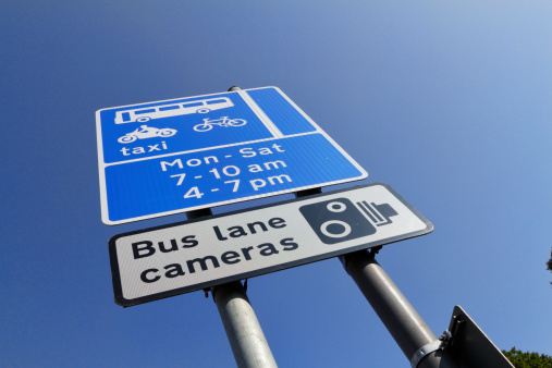 This is a typical sign alongside a bus lane in England. From the top, it describes: 1. Permitted traffic – buses, taxis, motorbikes and bicycles. 2. Times during which the bus lane is in operation – from Monday to Saturday at rush-hour times. 3. Warning sign that bus lane cameras are in operation. These cameras can be used as evidence of violations.