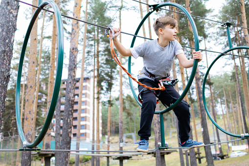 A side-view shot of a young boy smiling and playing on a summers day in the North East of England. The young boy is holding onto a swing rope and swinging from side to side.
