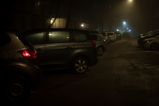 Car at night in parking lot. Cars in city. Parking in evening at house. Transport is on road.
