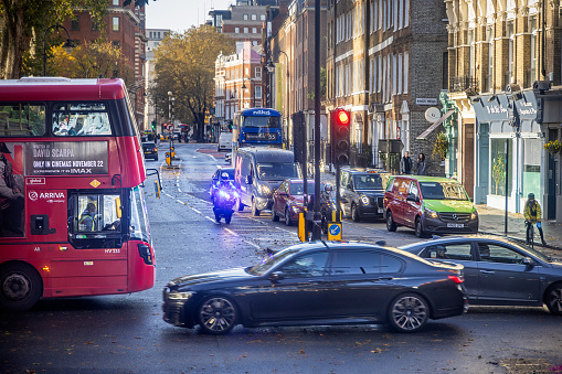 Clerkenwell Road, London, England - November 13th 2023: Police officer with emergency light on a motorbike in traffic in the afternoon dusk light seen from the upper level of a double-decker bus