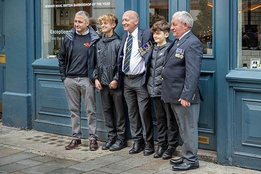 Maiden Lane, London, England - November 12th 2023:  Family group of men from different generations posing for a photo outside a pub on Remembrance Day