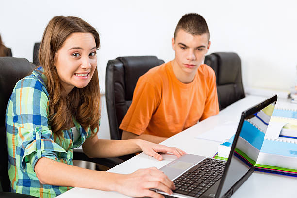 Teenage girl shrugging while using laptop