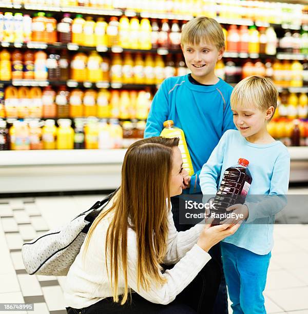 Счастливый Детей Помогая Мать Смотреть Для Фруктового Сока В Супермаркете — стоковые фотографии и другие картинки 10-11 лет