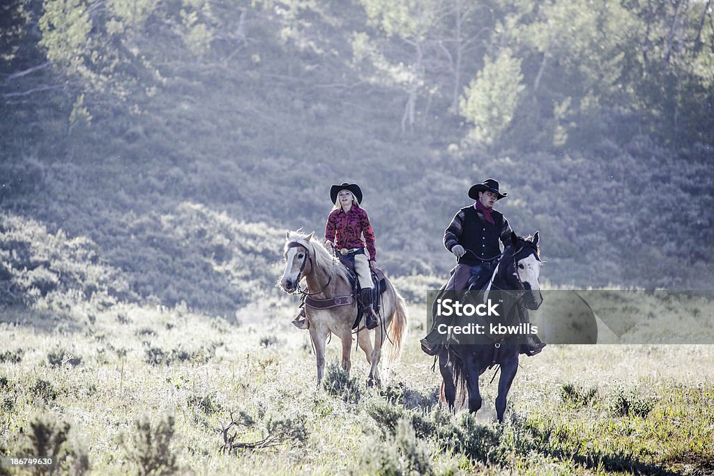 cowboy e parceiro passeio em iluminação de Montana manhã - Foto de stock de Cavalo - Família do cavalo royalty-free