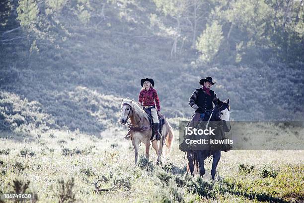 Foto de Cowboy E Parceiro Passeio Em Iluminação De Montana Manhã e mais fotos de stock de Cavalo - Família do cavalo