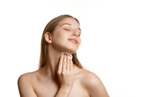 retrato de mujer con piel bien cuidada, toallitas la piel con esponja con tónico con vitaminas y minerales para una piel suave sobre fondo blanco. - human skin sparse washing face human face fotografías e imágenes de stock