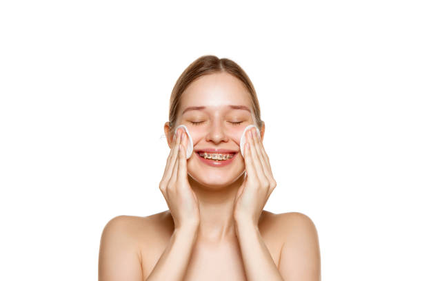 retrato de mujer sonriente limpia la piel con esponja con tónico con vitaminas y minerales para una piel suave sobre fondo blanco. - human skin sparse washing face human face fotografías e imágenes de stock