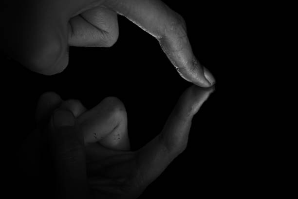 istock Reflection of a man's fingertips touching a mirror in low light. 1867506042