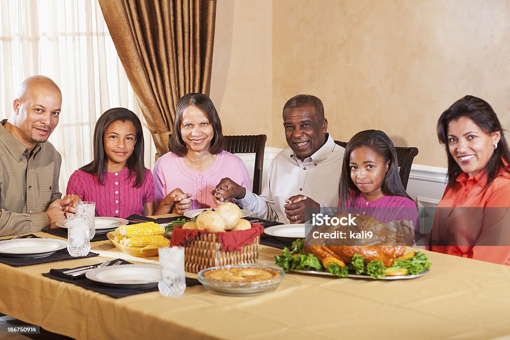 Нескольких поколений африканских Американский семья, Говорящая изящество перед праздничный ужин - Стоковые фото 10-11 лет роялти-фри