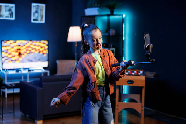 istock Kid doing content creation for children, utilizing cellphone on selfie stick to produce dance videos 1867519739