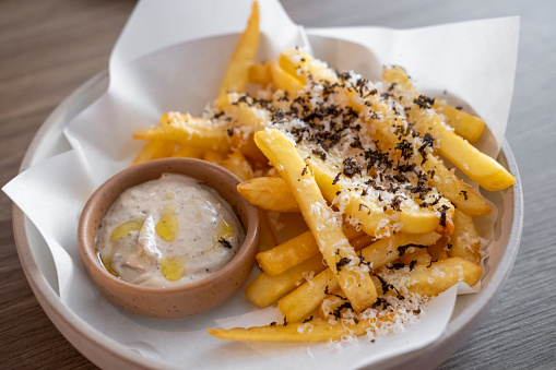 Close up of French Fries with cheese and black truffle sauce