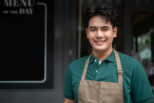Young Asian man cafe owner entrepreneur smiling in coffee shop, small business concept