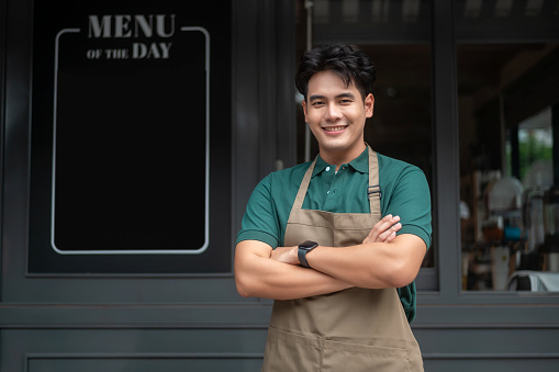 Young Asian man cafe owner entrepreneur smiling in coffee shop, small business concept
