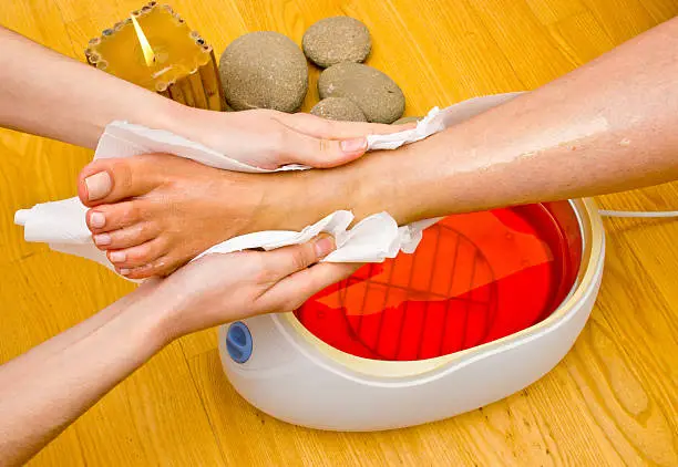 woman foot treatment in paraffin bath at the spa