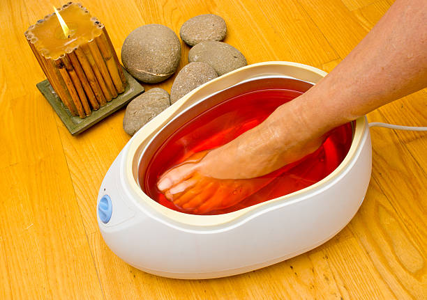 A woman soaking her feet in a paraffin bath at a spa stock photo