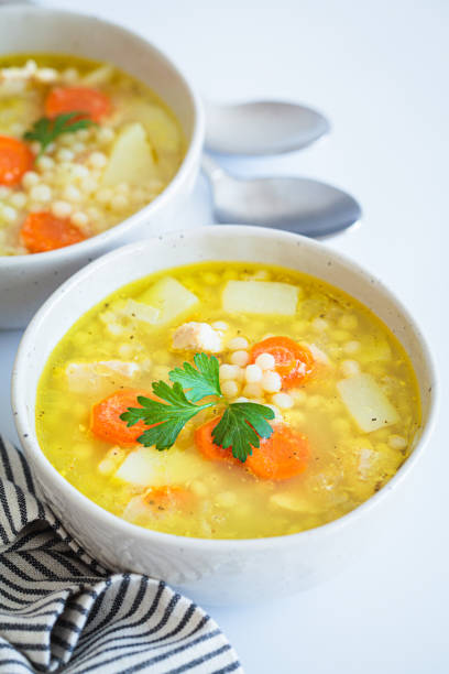 istock Chicken soup with vegetables and ptimtim - Israeli couscous, white background. 1867551287