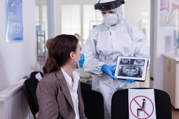 istock Stomatologist in protective suit pointing on digital x-ray of tooth 1867565641