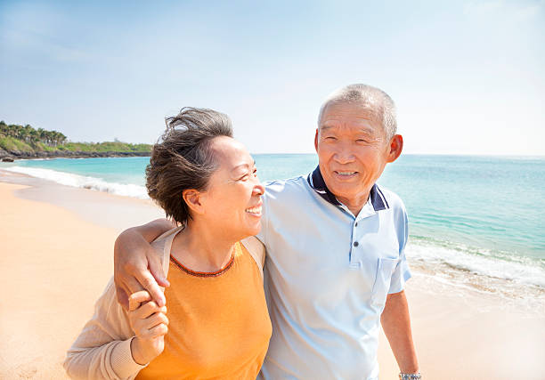 feliz asiática de ancianos caminando en la playa - couple mature adult action walking fotografías e imágenes de stock