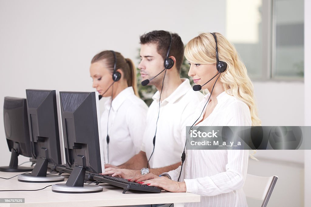 Group of customer service representatives. Group of customer service stuff at work sitting in a row and working. Adult Stock Photo