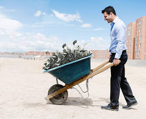 Rich man carrying money Rich man carrying loads of money in a wheelbarrow wheelbarrow stock pictures, royalty-free photos & images