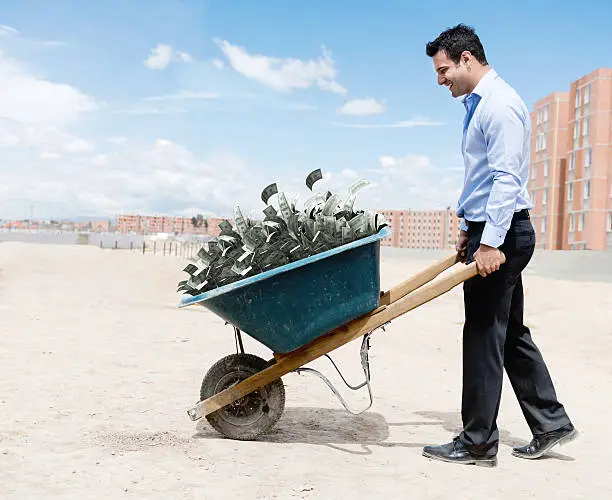 Rich man carrying loads of money in a wheelbarrow