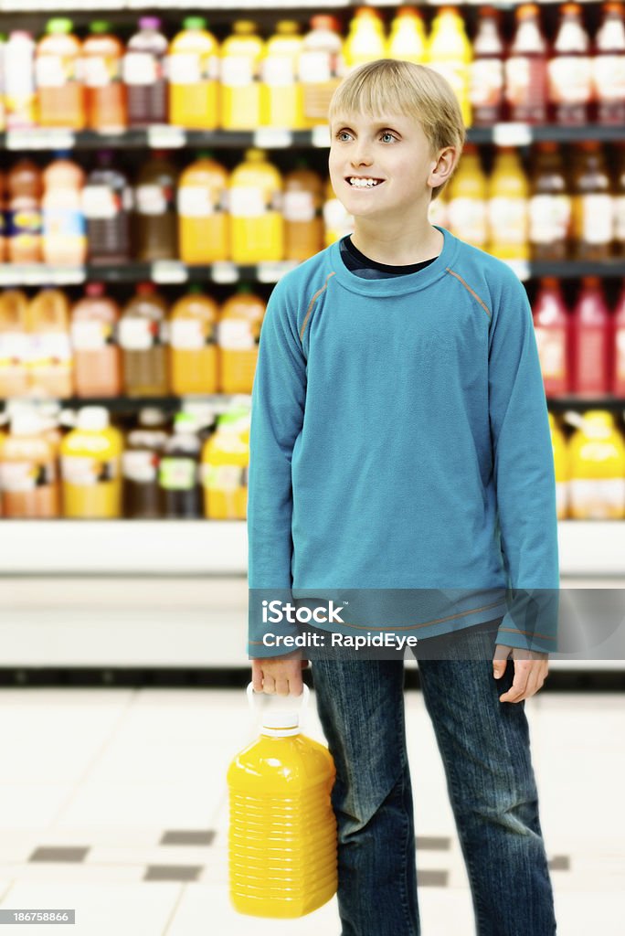 Écolier garçon blond souriant obtention des jus d'orange dans un supermarché - Photo de 10-11 ans libre de droits