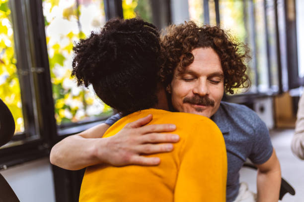 istock Man and woman hugging at a group therapy session, overcoming problem together 1867611221