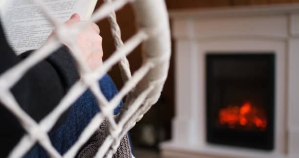 istock Serene man engrossed in book by warm fireplace, epitomized solitude. Scene captures essence of peaceful loneliness, perfect for evoking sense of solitary comfort. Downshifting concept 1867614874