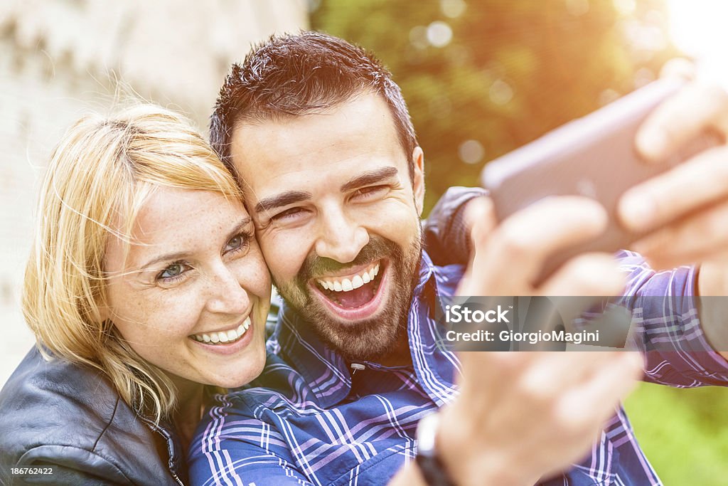 Mid adultos pareja tomando fotos con un teléfono inteligente - Foto de stock de 25-29 años libre de derechos