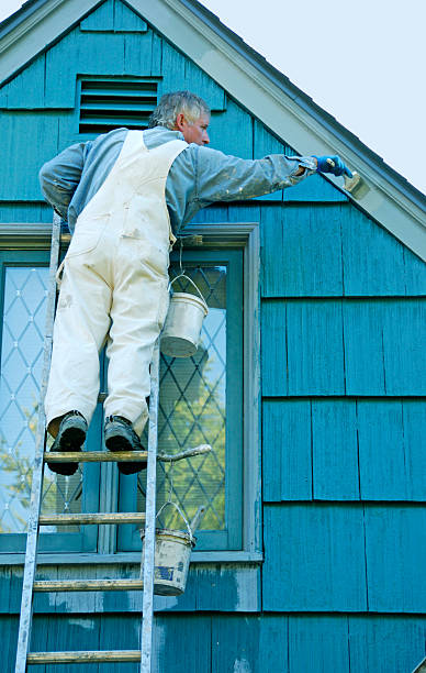 istock Man on ladder painting house trim 186762840
