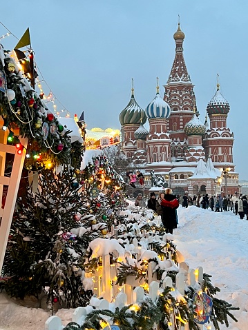 Moscow, Russia - December 16, 2023: Crowds of people on Red Square, enjoying snow, games and Christmas market. St. Basil Cathedral in snow